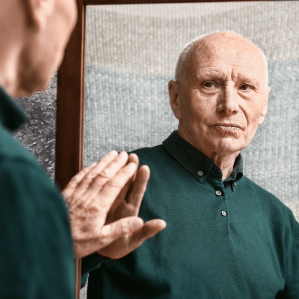 A man looking at himself in the mirror, but his reflection appears aged or rusted, symbolizing cellular damage.