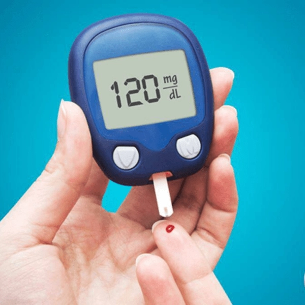 A hand holding a digital blood glucose meter displaying a reading of 120 mg/dL, with a test strip collecting a blood sample from a fingertip.