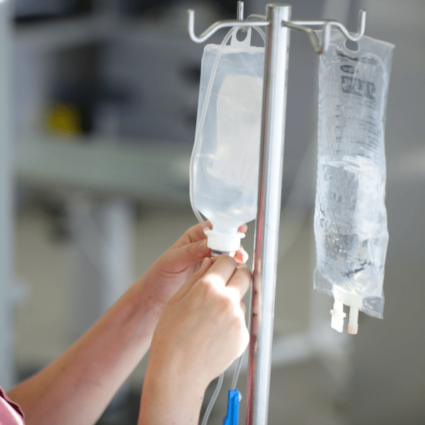Close-up of hands setting up an IV drip, illustrating intravenous magnesium therapy for fast-acting nutritional support.