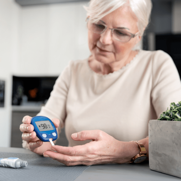 Mature woman checking her blood sugar level at home, illustrating the connection between hormones, insulin, and metabolic health.