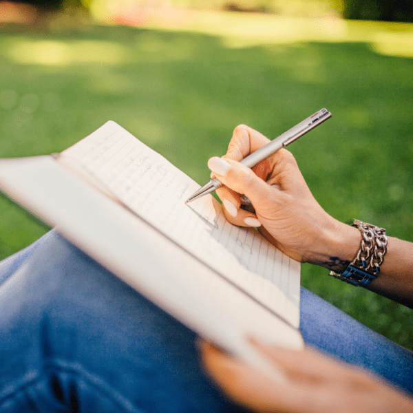 Person sitting in the grass and writing in a journal