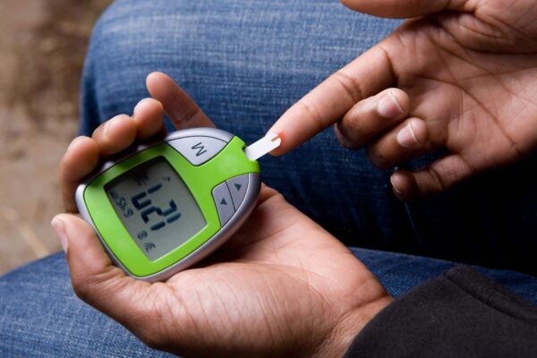 African American Woman Tests Blood Sugar.  Blood sugar is slightly high.