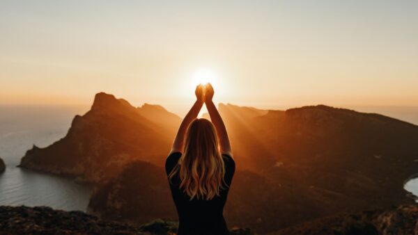 Woman wiht hands stretched out to the sun.