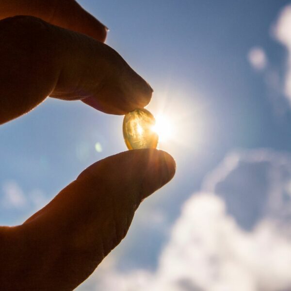 Close-up of a Vitamin D capsule held up to the sun.