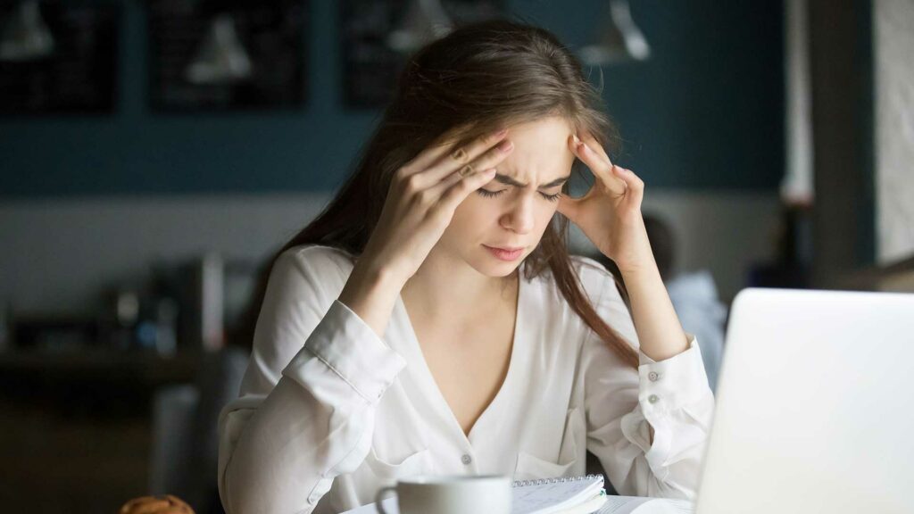 Woman working under stress holding head