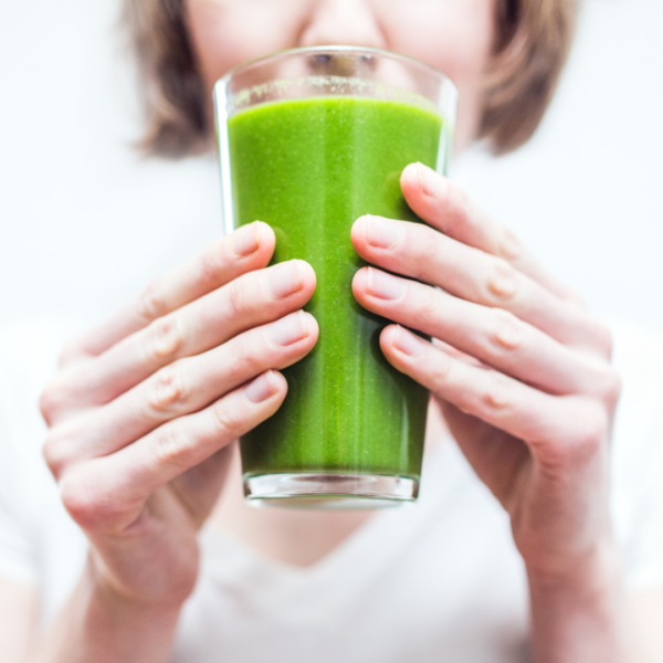 Woman drinking a glass of green smoothie