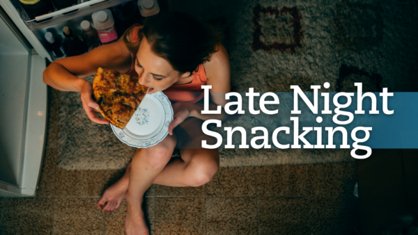 Woman eating a slice of pizza in front of the refrigerator