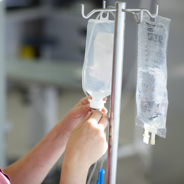 Close-up of hands setting up an IV drip, illustrating intravenous magnesium therapy for fast-acting nutritional support.