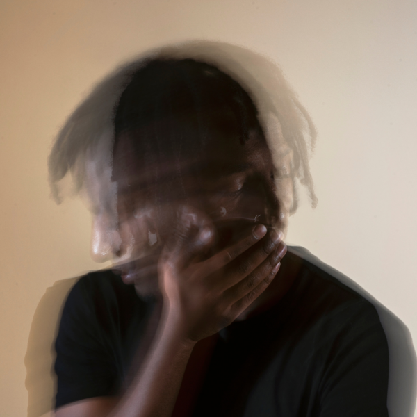 Blurred image of a distressed man with his face in his hand, symbolizing confusion, emotional overwhelm, or mental health struggles such as anxiety or trauma.