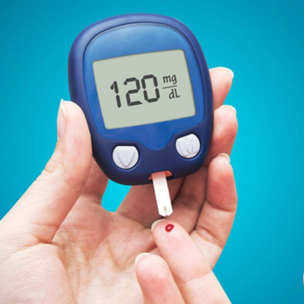 A hand holding a digital blood glucose meter displaying a reading of 120 mg/dL, with a test strip collecting a blood sample from a fingertip.