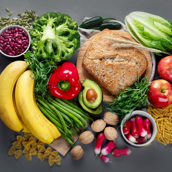 Assortment of fresh, healthy foods including bananas, apples, broccoli, beans, whole grain bread, lettuce, and nuts, emphasizing nutritious eating for weight management.