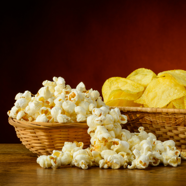 Wicker baskets filled with popcorn and potato chips on a wooden table