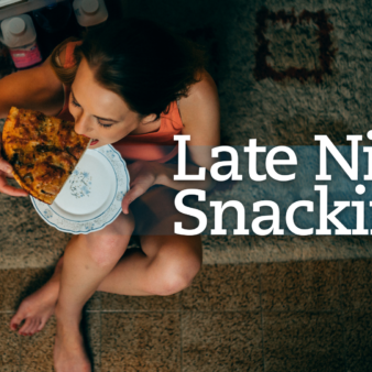 Woman eating a slice of pizza in front of the refrigerator